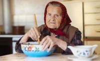 very old woman preparing food in her old country style kitchen