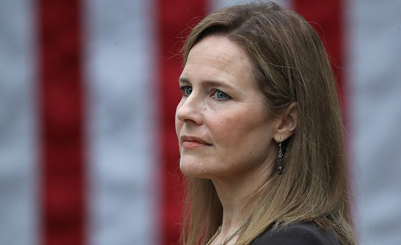 amy coney barrett in front of an american flag